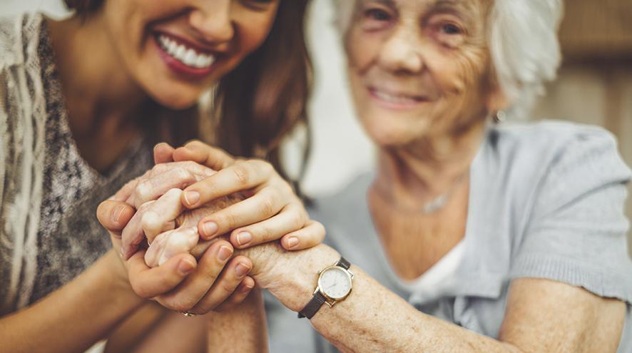 care worker and senior woman holding hands