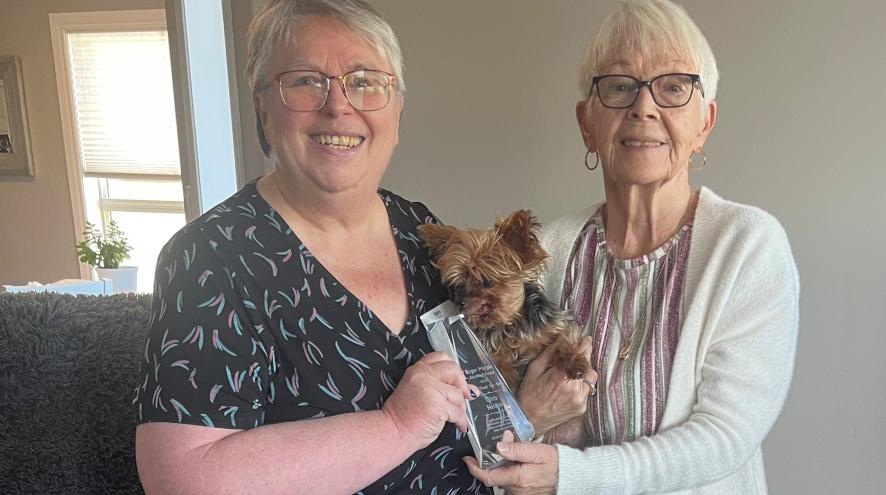 Picture of Barb (Society staff member) and Chris Nelson (award recipient) holding award.