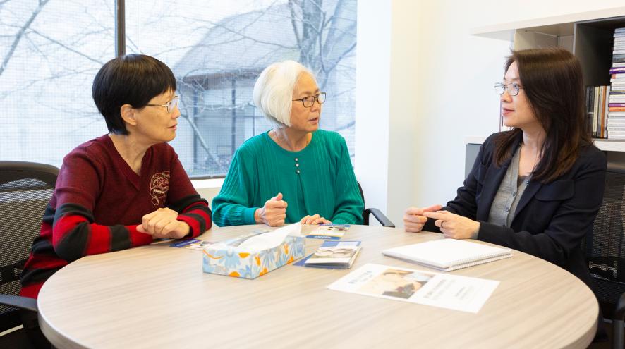 Three women gathered round a table talking.