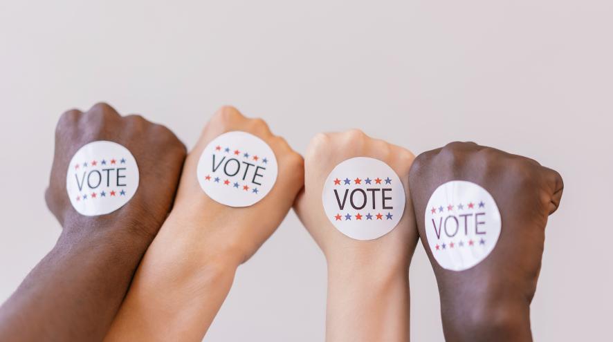 Four hands with stickers reading vote
