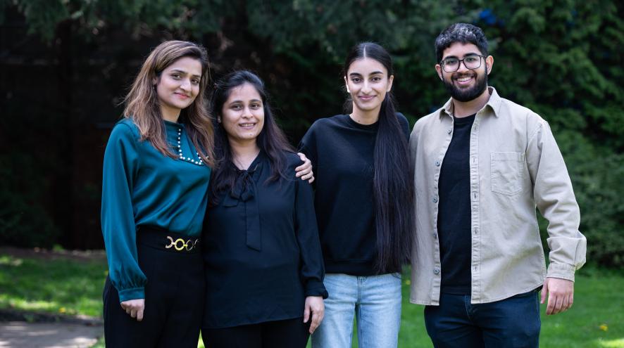 four people standing on the grass and smiling