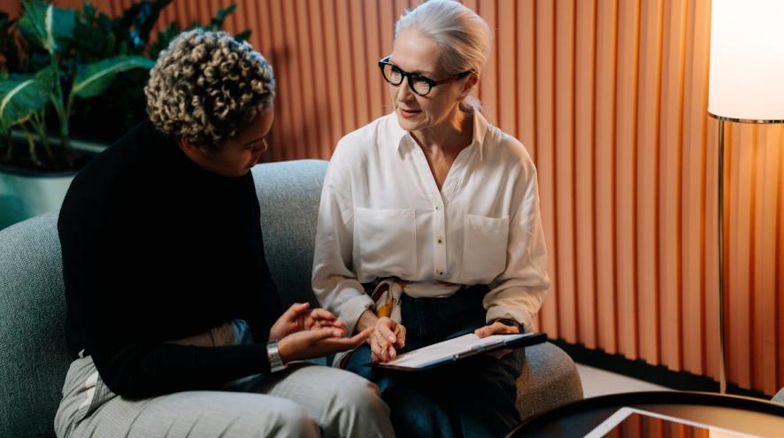 An older woman and a researcher review a form together on a clip board