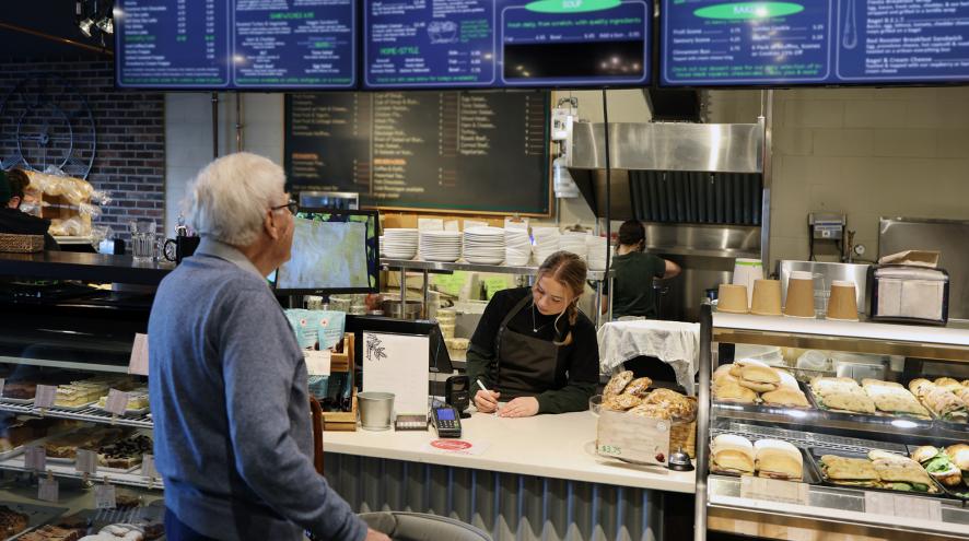 A person looking at a large menu board at a cafe