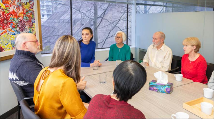 Seven adults sitting around a table in conversation.