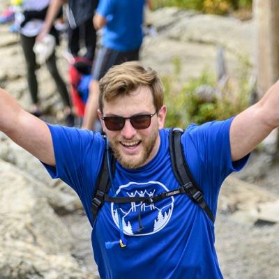 Man wearing a branded Climb t-shirt with his arms in the air triumphantly.