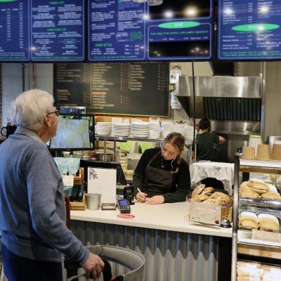 A person looking at a large menu board at a cafe