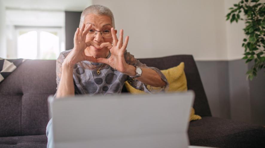 une personne fait un coeur avec ses mains face à l'écran