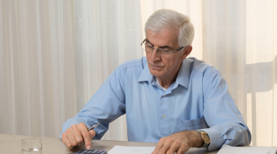 un homme âgé faisant des calculs pour ses impots