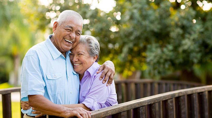 Senior couple laughing together on their balcony.