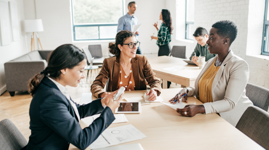 Three women sitting around desk