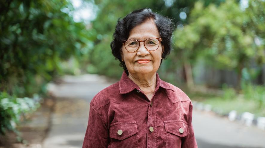 Elderly Asian woman in a red button-up.