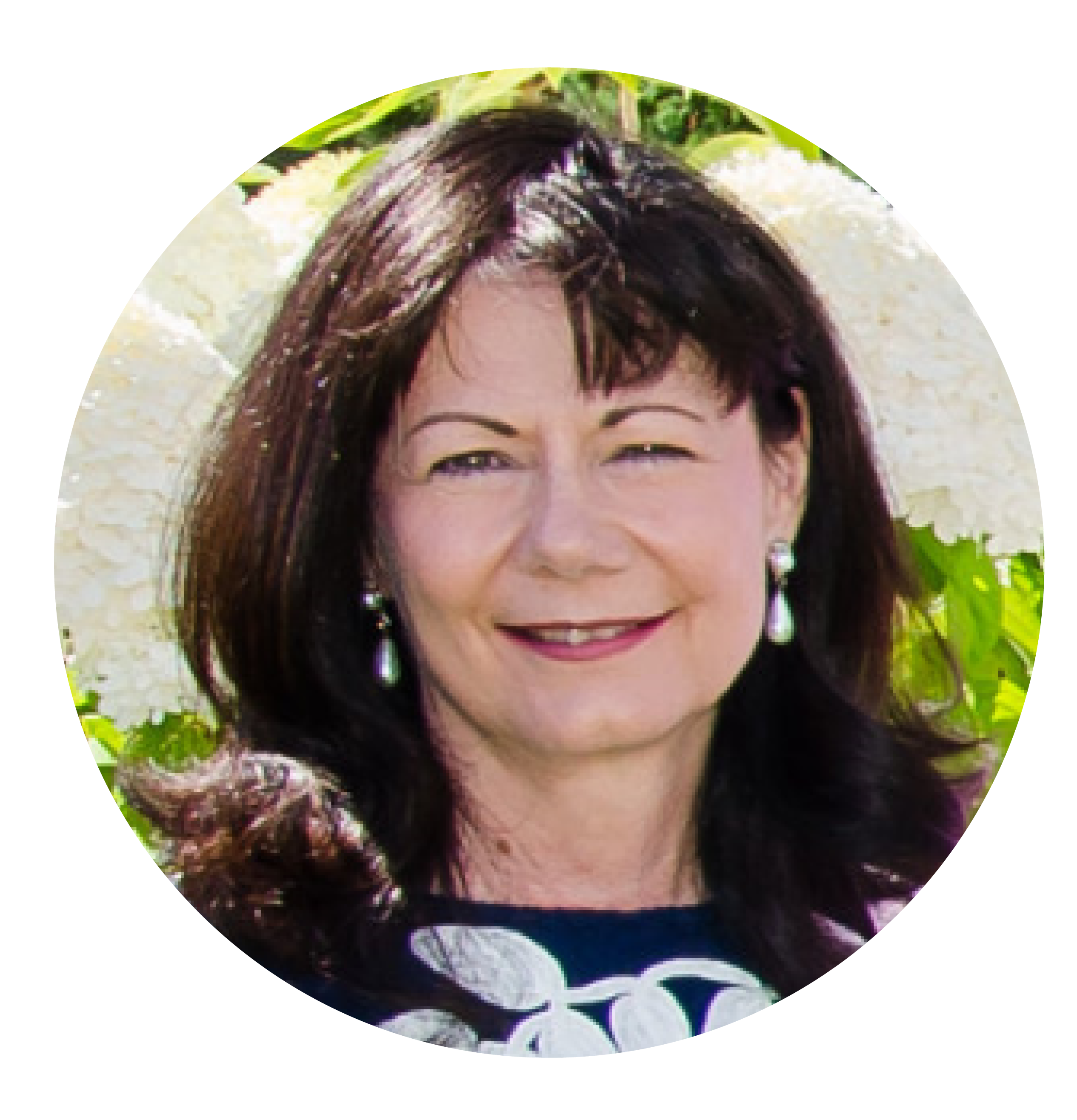 Woman with medium length brown hair and bangs and white earrings