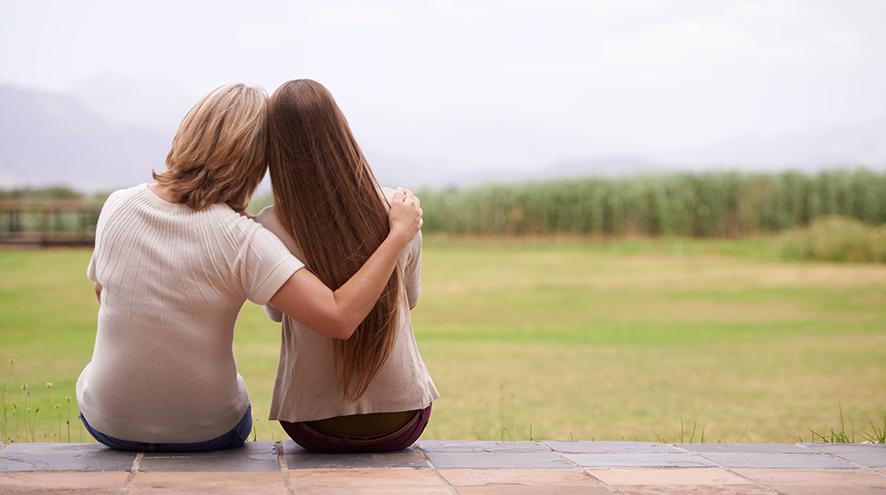 Mother and daughter looking at the forested horizon together.