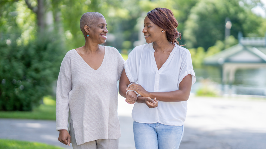 Older woman walks arm in arm with younger woman