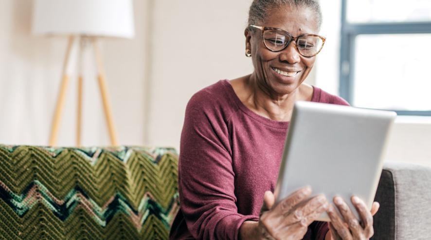 An older woman reading a tablet at home