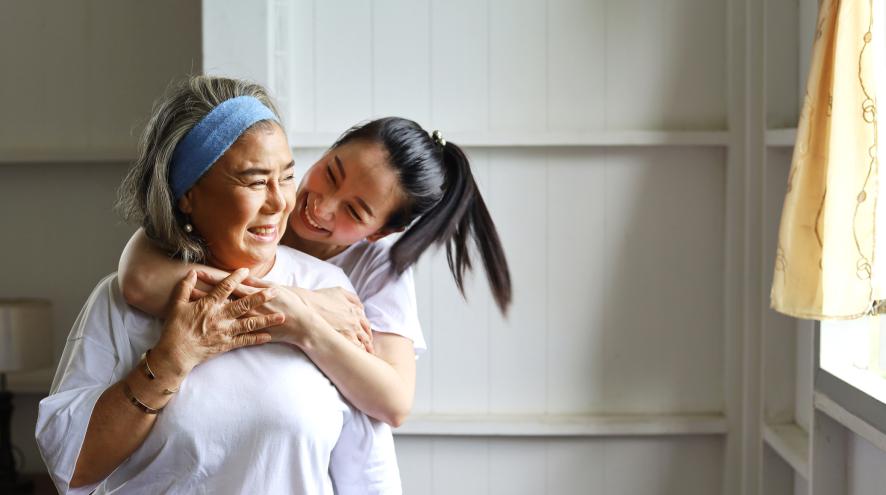 Young woman hugging an elder playfully