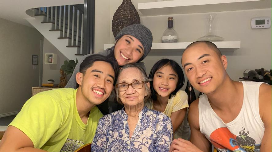Four young siblings smiling around their grandmother
