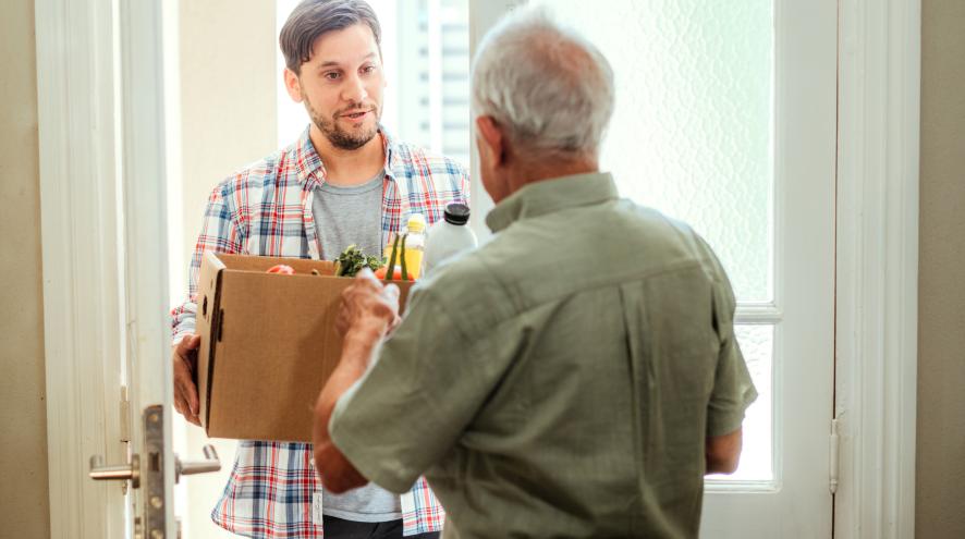 Neighbour delivering groceries to senior man