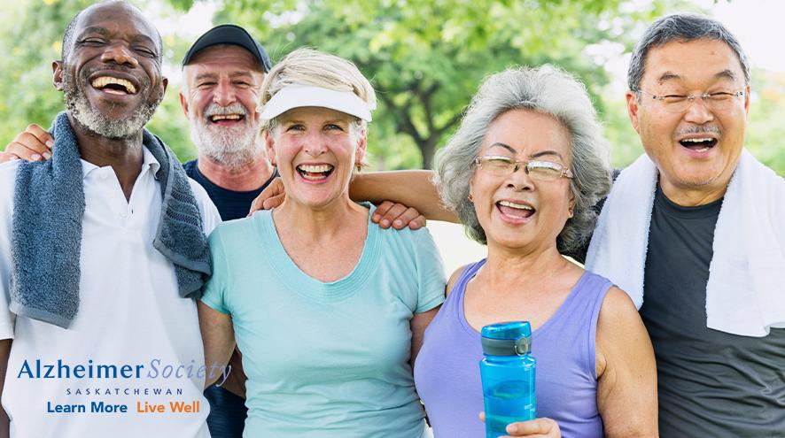 A group of people of mixed ethnicities posing after an outdoor exercise class.