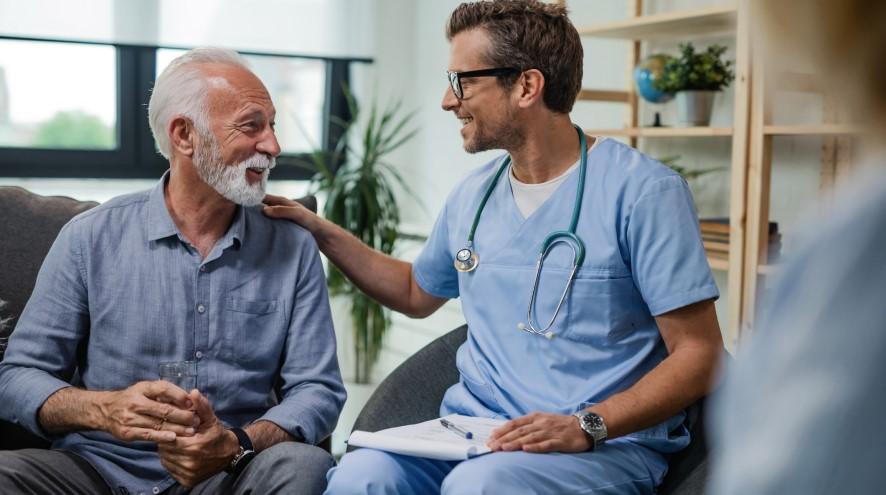 A young doctor places a reassuring hand on his senior patient.